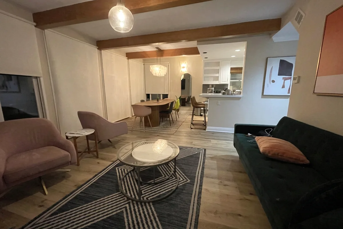 A real living room photographed from a corner, showing two walls, the floor, and a window before an AI redesign